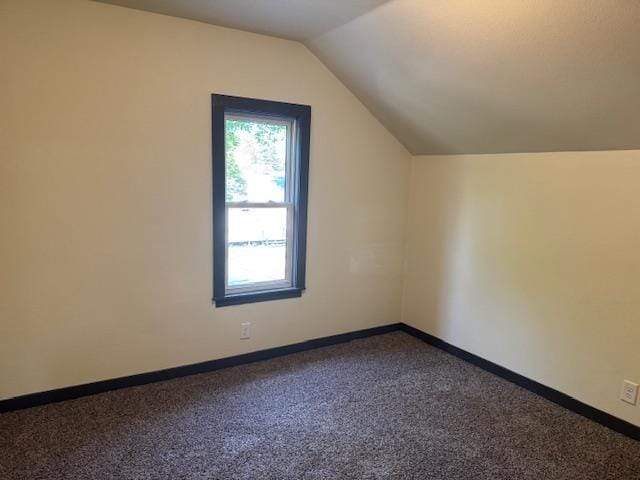 616 10th St, Minot, ND 58703 - additional living space featuring dark carpet, lofted ceiling, and baseboards