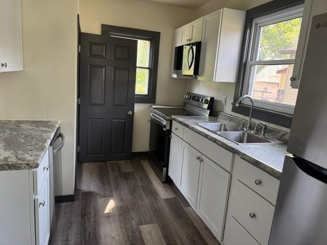 616 10th St, Minot, ND 58703 - kitchen featuring stainless steel appliances, a sink, white cabinetry, dark wood finished floors, and light countertops