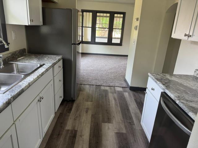 616 10th St, Minot, ND 58703 - kitchen featuring stainless steel dishwasher, a sink, arched walkways, and white cabinets