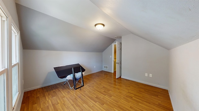 917 4th Ave, Minot, ND 58703 - additional living space with light wood-style floors, lofted ceiling, and baseboards