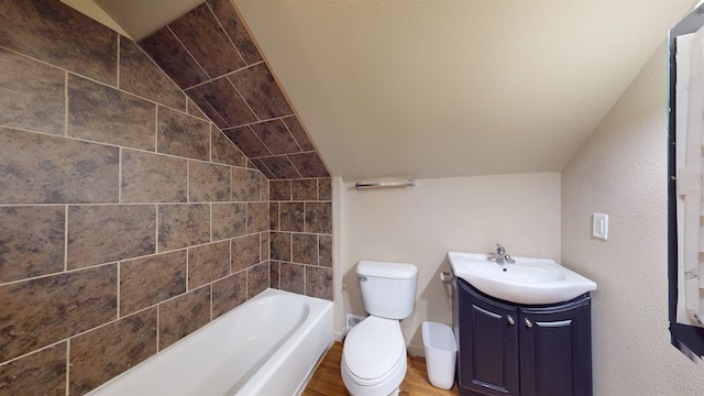 917 4th Ave, Minot, ND 58703 - bathroom with toilet, vanity, lofted ceiling, wood finished floors, and washtub / shower combination