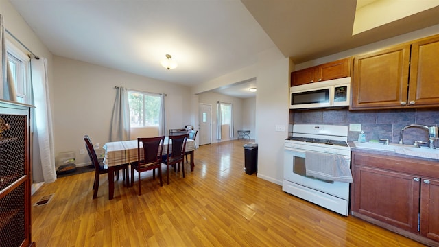 917 4th Ave, Minot, ND 58703 - kitchen featuring white appliances, light wood-type flooring, decorative backsplash, and light countertops