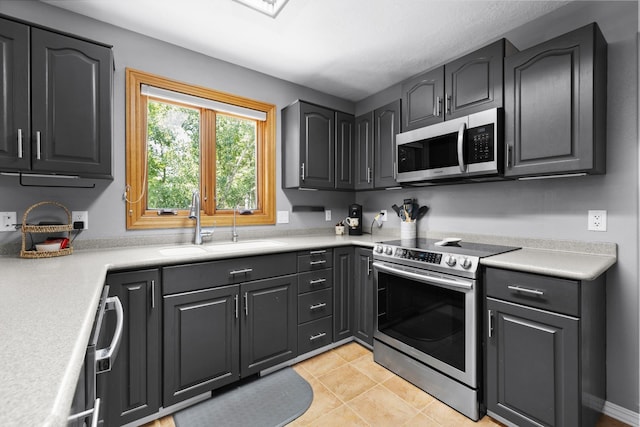 3304 12th St, Minot, ND 58701 - kitchen featuring stainless steel appliances, a sink, light countertops, and light tile patterned flooring
