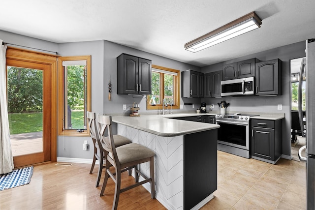 3304 12th St, Minot, ND 58701 - kitchen with stainless steel appliances, a peninsula, a kitchen breakfast bar, and light countertops