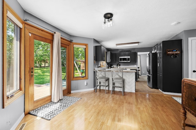 3304 12th St, Minot, ND 58701 - kitchen with appliances with stainless steel finishes, a peninsula, baseboards, and light wood-style flooring