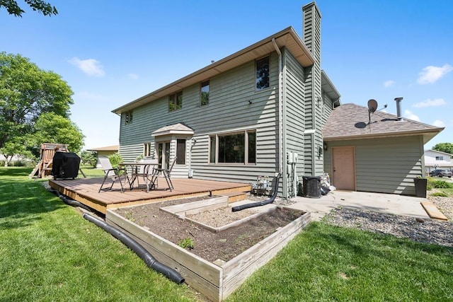 3304 12th St, Minot, ND 58701 - back of property featuring a chimney, a yard, a wooden deck, a garden, and a patio
