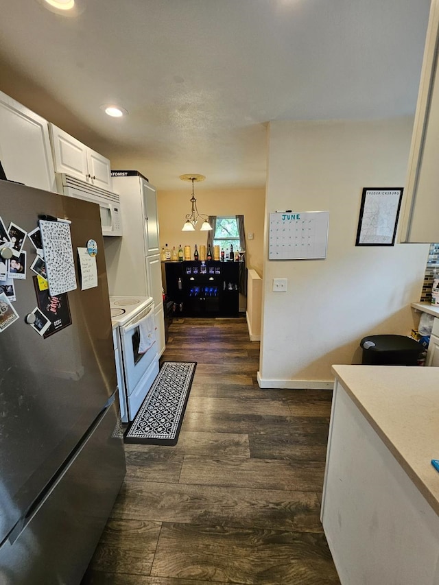320 7th St, Minot, ND 58703 - kitchen with white appliances, light countertops, white cabinets, dark wood-type flooring, and decorative light fixtures
