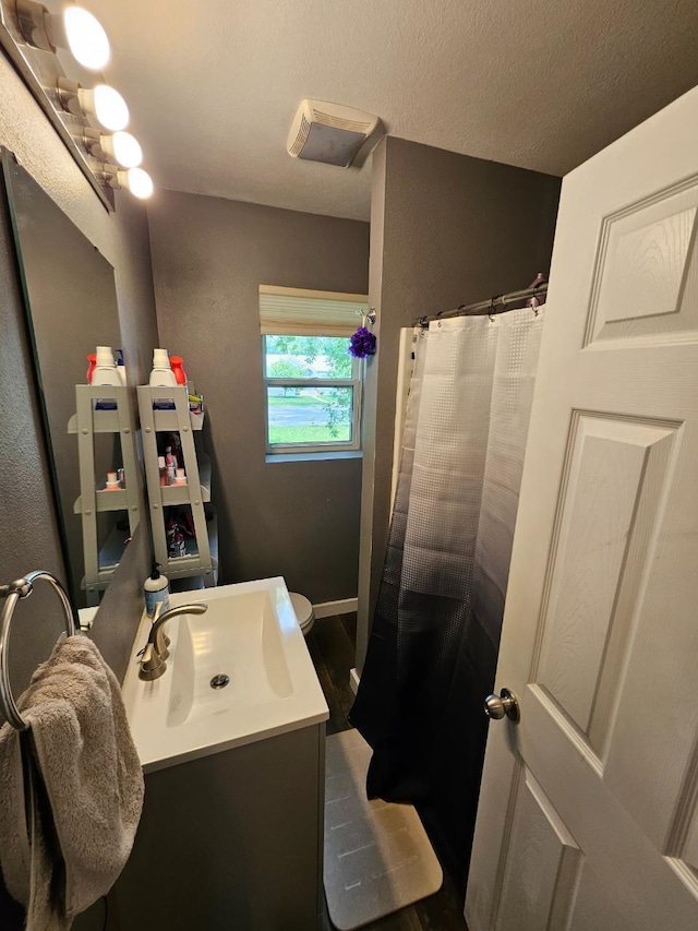 320 7th St, Minot, ND 58703 - bathroom featuring vanity, wood finished floors, a shower with shower curtain, and baseboards