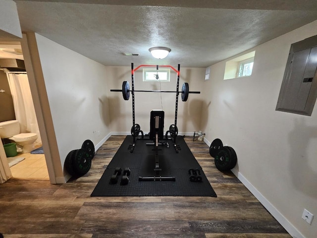 320 7th St, Minot, ND 58703 - workout area featuring electric panel, dark wood finished floors, baseboards, a textured ceiling, and healthy amount of natural light