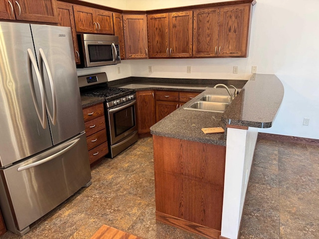 1400 34th Ave, Minot, ND 58701 - kitchen featuring appliances with stainless steel finishes, a peninsula, brown cabinetry, stone finish floors, and dark stone countertops
