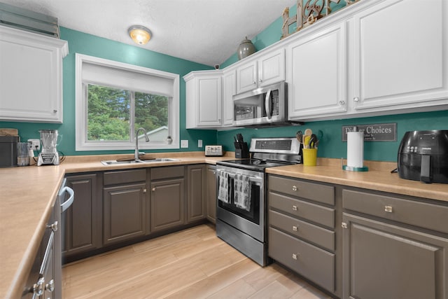 1705 SW Evergreen Ave, Minot, ND 58701 - kitchen with stainless steel appliances, gray cabinets, white cabinets, and a textured ceiling