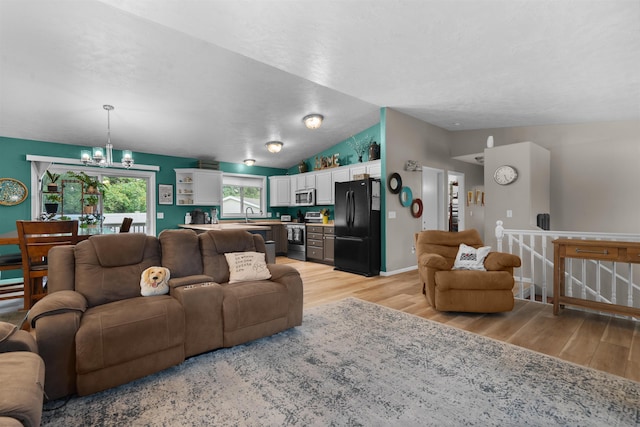 1705 SW Evergreen Ave, Minot, ND 58701 - living room with light wood-style floors, a chandelier, and lofted ceiling
