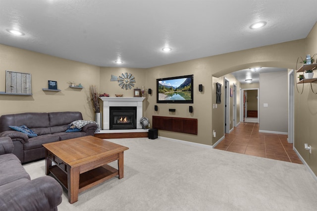 1705 SW Evergreen Ave, Minot, ND 58701 - carpeted living room featuring arched walkways, a glass covered fireplace, recessed lighting, and tile patterned flooring