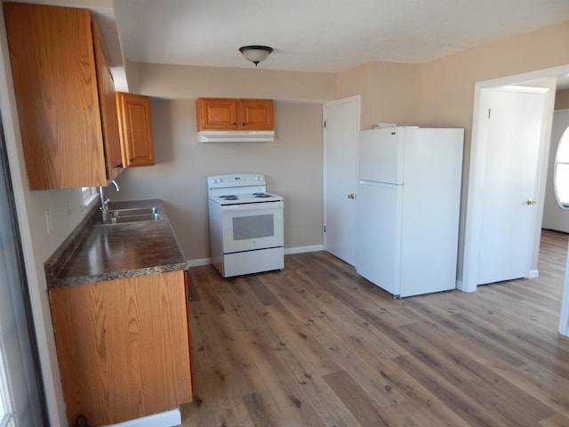 2014 4th St, Minot, ND 58703 - kitchen featuring white appliances, under cabinet range hood, dark countertops, light wood-style floors, and brown cabinetry