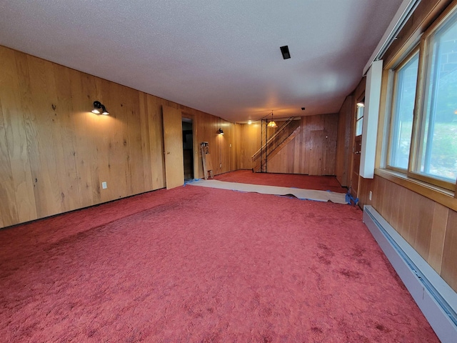 1000 21st St, Minot, ND 58703 - spare room with wood walls, baseboard heating, stairs, carpet floors, and a textured ceiling