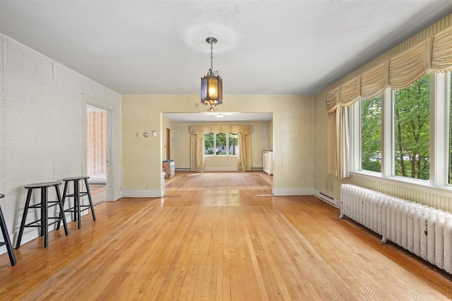 306 2nd St, Towner, ND 58788 - unfurnished dining area with radiator, light wood-style floors, a baseboard heating unit, and a baseboard radiator