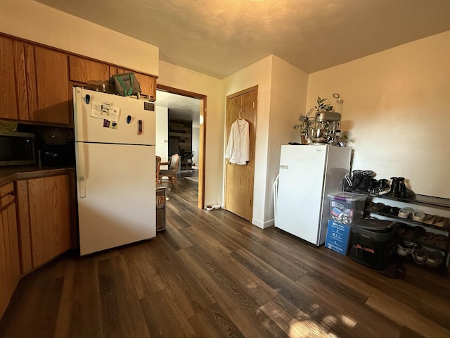 3301 SE 1st St, Minot, ND 58701 - kitchen with freestanding refrigerator, stainless steel microwave, brown cabinetry, and dark wood-style flooring