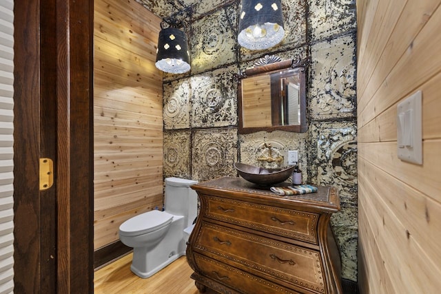 519 4th St, Minot, ND 58701 - half bathroom featuring vanity, wood finished floors, and wooden walls