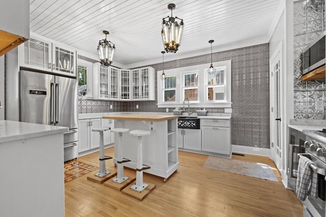 519 4th St, Minot, ND 58701 - kitchen with premium appliances, a chandelier, butcher block counters, light wood-style floors, and ornamental molding