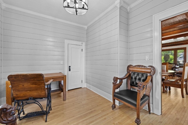 519 4th St, Minot, ND 58701 - sitting room featuring crown molding, light wood finished floors, wooden walls, and a chandelier
