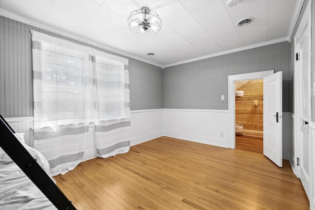 519 4th St, Minot, ND 58701 - unfurnished bedroom with ornamental molding, light wood-type flooring, and wainscoting