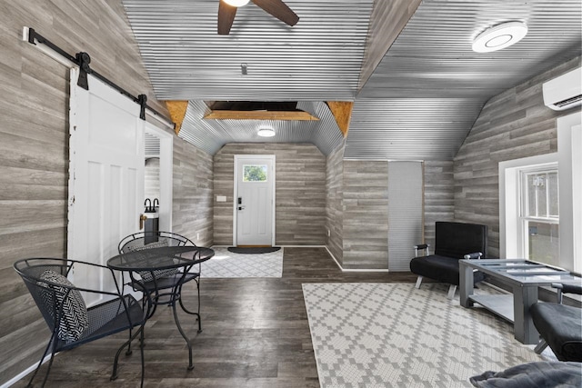 519 4th St, Minot, ND 58701 - living area with a barn door, ceiling fan, vaulted ceiling, wood finished floors, and a wall unit AC