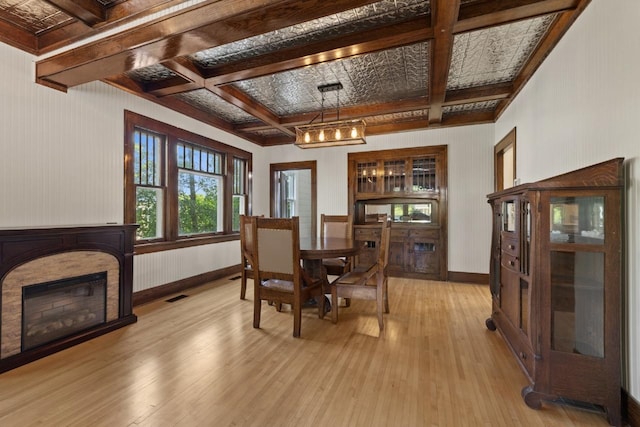 519 4th St, Minot, ND 58701 - dining space with coffered ceiling, light wood-style floors, a glass covered fireplace, and beamed ceiling