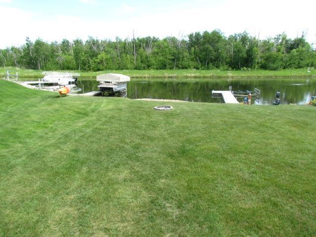 83 Hahns Bay Rd, Lake Metigoshe, ND 58318 - view of green lawn featuring a water view and a dock