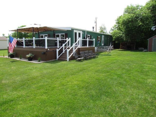 83 Hahns Bay Rd, Lake Metigoshe, ND 58318 - rear view of house featuring a wooden deck, a lawn, and a storage unit