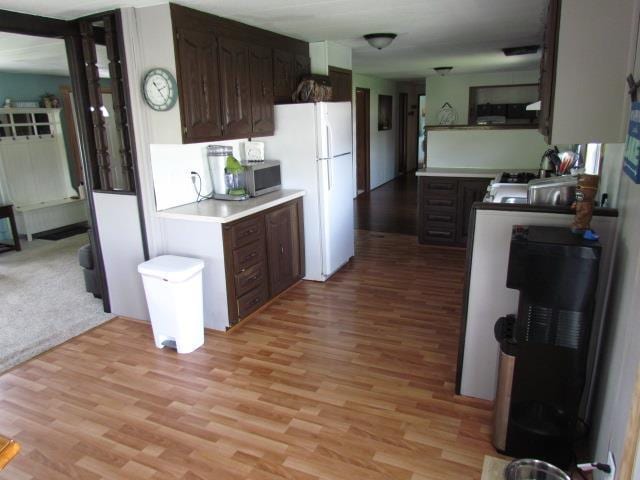 83 Hahns Bay Rd, Lake Metigoshe, ND 58318 - kitchen with freestanding refrigerator, light wood finished floors, light countertops, and dark brown cabinetry