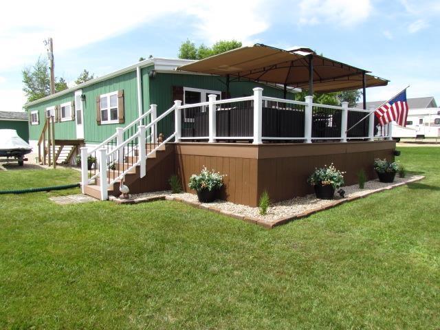 83 Hahns Bay Rd, Lake Metigoshe, ND 58318 - view of property exterior featuring a lawn and a deck