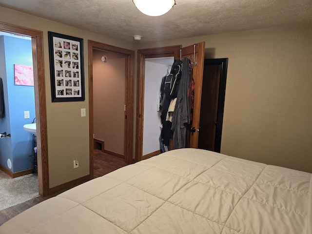209 University Ave, Minot, ND 58703 - bedroom with a closet, wood finished floors, ensuite bath, and a textured ceiling