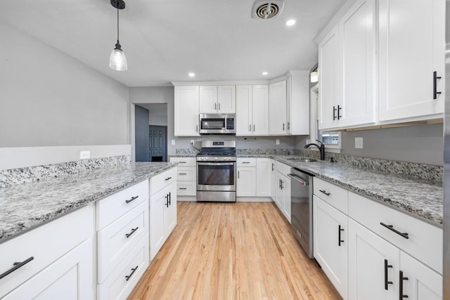 615 18th Ave, Minot, ND 58701 - kitchen with stainless steel appliances, light wood finished floors, recessed lighting, white cabinetry, and pendant lighting