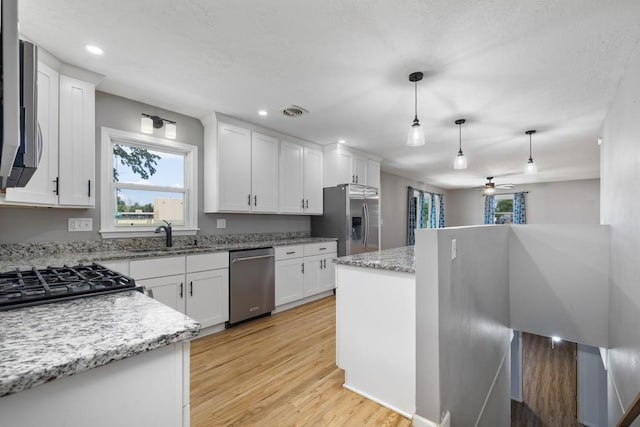 615 18th Ave, Minot, ND 58701 - kitchen featuring stainless steel appliances, ceiling fan, white cabinetry, light wood-type flooring, and pendant lighting