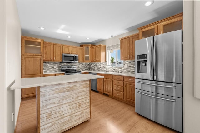1949 24th St, Minot, ND 58701 - kitchen with appliances with stainless steel finishes, light countertops, glass insert cabinets, decorative backsplash, and light wood-style floors