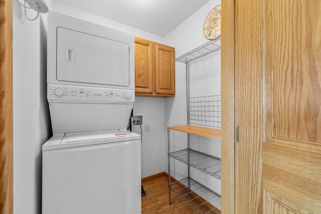 1949 24th St, Minot, ND 58701 - laundry area featuring cabinet space, stacked washer / dryer, and wood finished floors