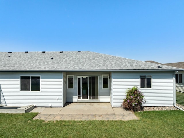 1949 24th St, Minot, ND 58701 - back of house with a shingled roof, a patio, and a lawn