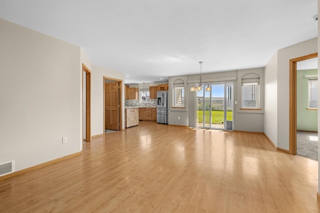 1949 24th St, Minot, ND 58701 - unfurnished living room featuring light wood-style floors and a chandelier