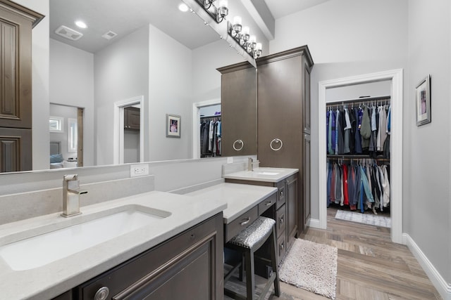 2009 35th Ave, Minot, ND 58701 - bathroom featuring double vanity, a spacious closet, and wood finished floors