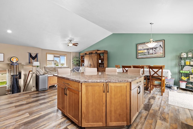 1808 28th St, Minot, ND 58703 - kitchen featuring wood finished floors, vaulted ceiling, a ceiling fan, a center island, and hanging light fixtures