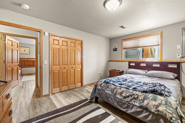 1808 28th St, Minot, ND 58703 - bedroom with light wood-style floors, a textured ceiling, and a closet