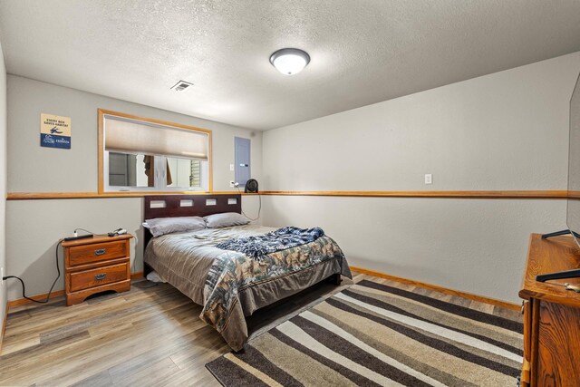 1808 28th St, Minot, ND 58703 - bedroom with light wood finished floors and a textured ceiling