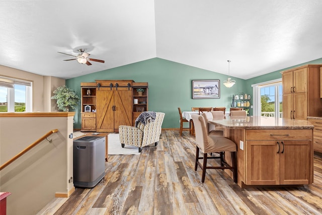 1808 28th St, Minot, ND 58703 - kitchen featuring wood finished floors, ceiling fan, vaulted ceiling, pendant lighting, and a kitchen breakfast bar