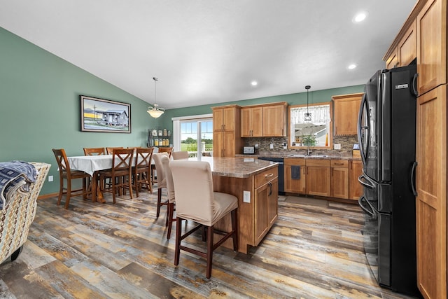 1808 28th St, Minot, ND 58703 - kitchen featuring black appliances, plenty of natural light, a center island, wood finished floors, and lofted ceiling