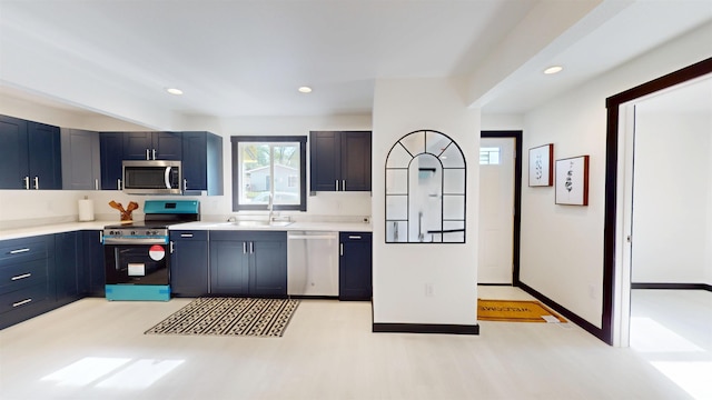 1113 10th St, Minot, ND 58703 - kitchen with appliances with stainless steel finishes, light wood-style floors, light countertops, blue cabinets, and recessed lighting