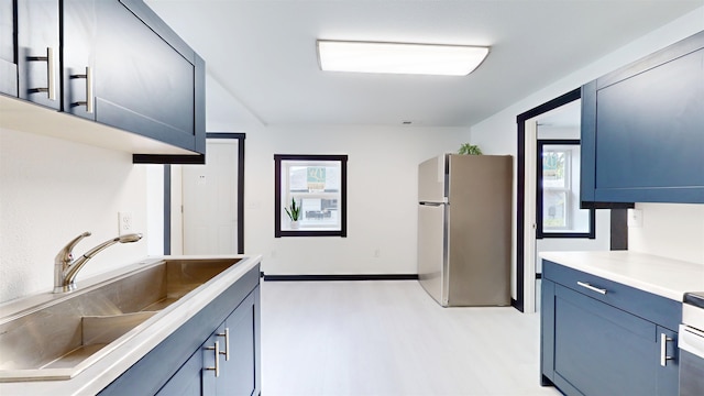1113 10th St, Minot, ND 58703 - kitchen with freestanding refrigerator, light wood-style flooring, plenty of natural light, and light countertops