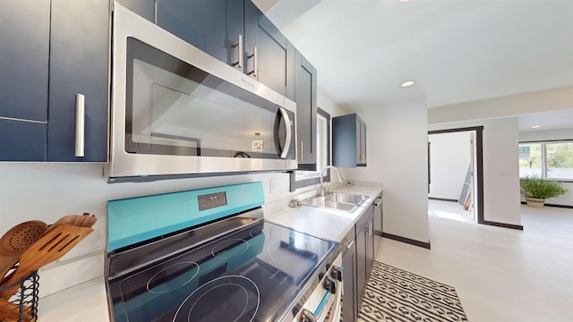 1113 10th St, Minot, ND 58703 - kitchen featuring stainless steel appliances, light countertops, light wood-style flooring, recessed lighting, and blue cabinets