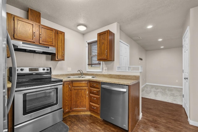 606 19th Ave Unit 7, Minot, ND 58701 - kitchen with appliances with stainless steel finishes, under cabinet range hood, dark wood-style flooring, brown cabinets, and recessed lighting
