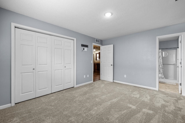 606 19th Ave Unit 7, Minot, ND 58701 - unfurnished bedroom featuring a textured ceiling, carpet flooring, a closet, and ensuite bath