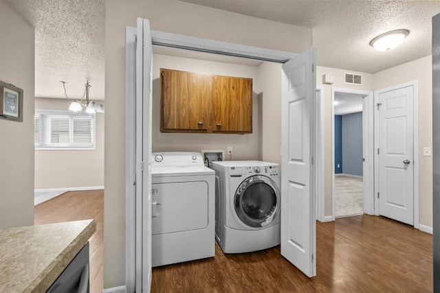 606 19th Ave Unit 7, Minot, ND 58701 - laundry room featuring cabinet space, independent washer and dryer, a textured ceiling, a chandelier, and dark wood finished floors